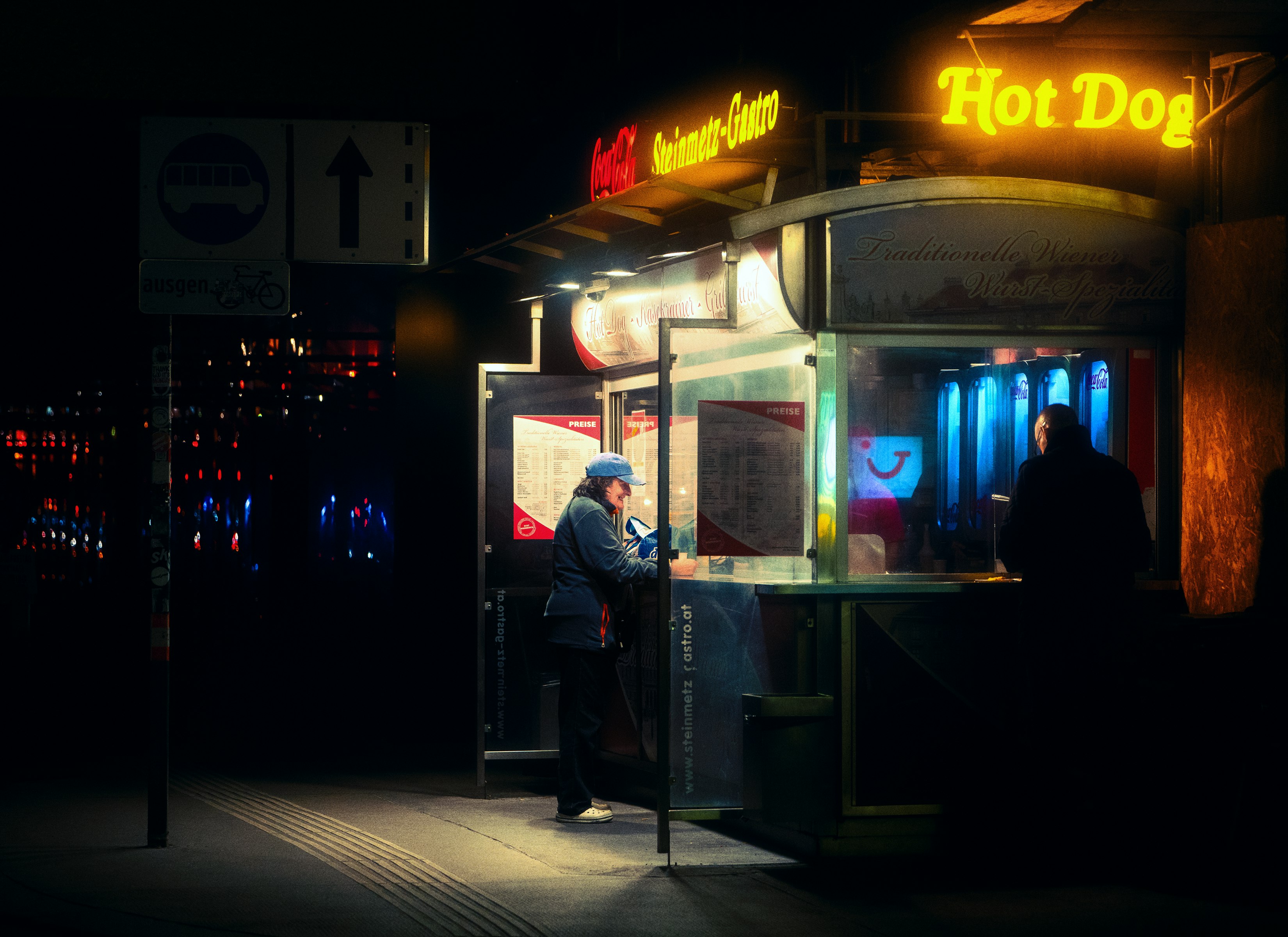 man in black jacket standing near store during night time